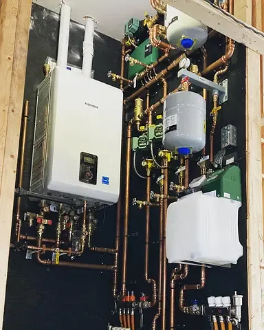 Immaculate hydronic boiler room installed by Burt's Breeze — wall-hung boiler with neatly organized copper manifolds